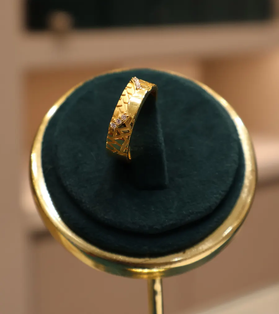 A gold band ring on a green velvet stand