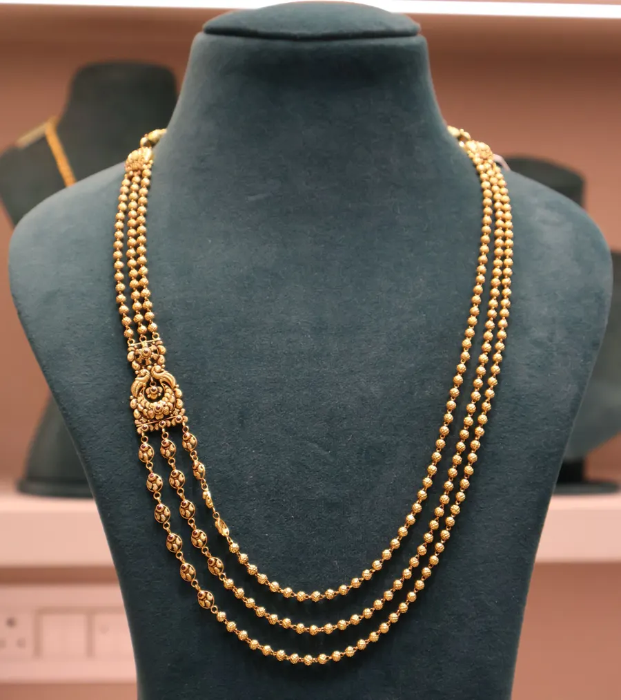 A three-strand gold bead chain on a bust
