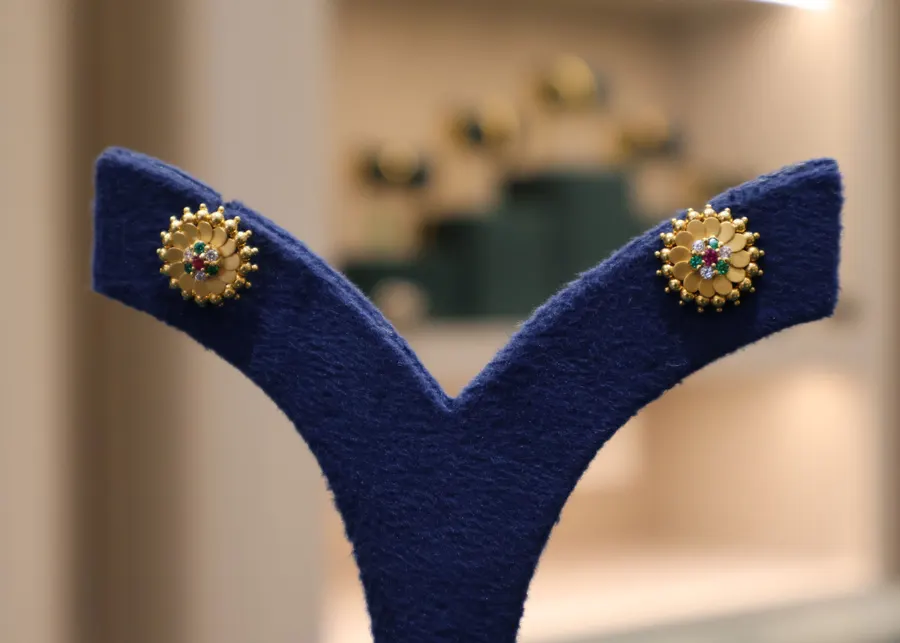 A small round gold stud on a display stand